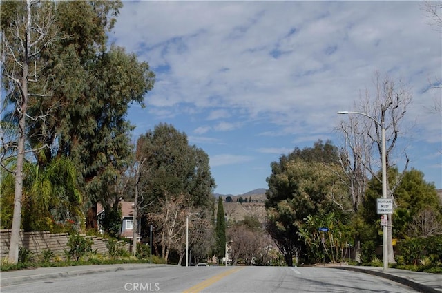 view of road featuring street lights, curbs, and sidewalks