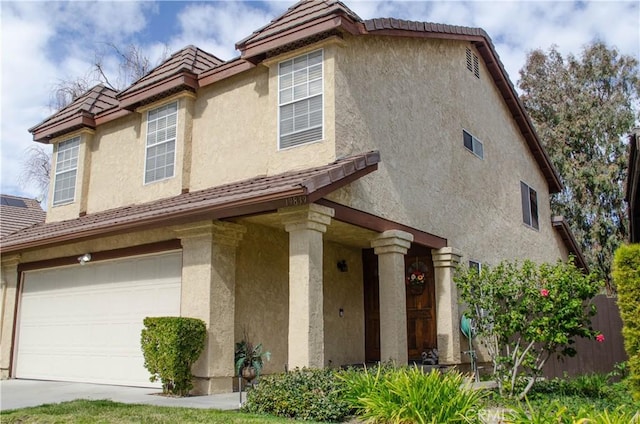 view of side of property featuring a tiled roof, an attached garage, and stucco siding