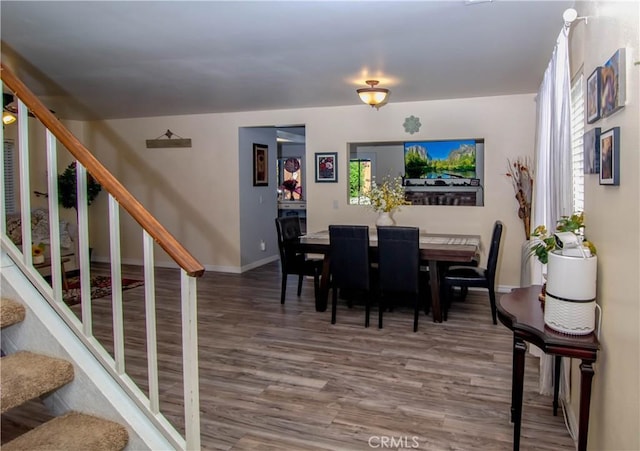 dining space with stairs, baseboards, and wood finished floors