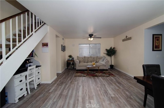 living area featuring ceiling fan, stairway, wood finished floors, and baseboards