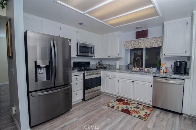 kitchen featuring white cabinets, light wood-type flooring, stainless steel appliances, and a sink