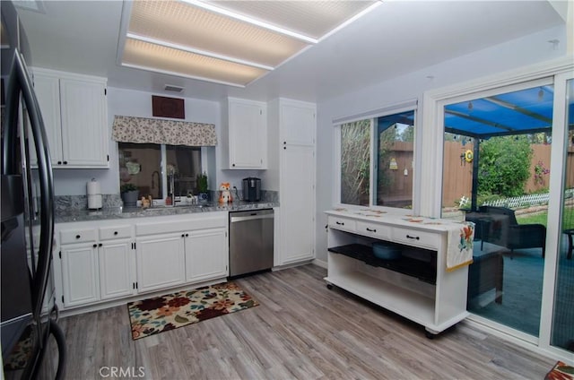 kitchen with light wood-style flooring, a sink, white cabinetry, stainless steel dishwasher, and freestanding refrigerator