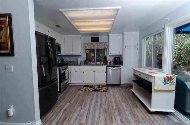 kitchen with appliances with stainless steel finishes, wood finished floors, visible vents, and white cabinets