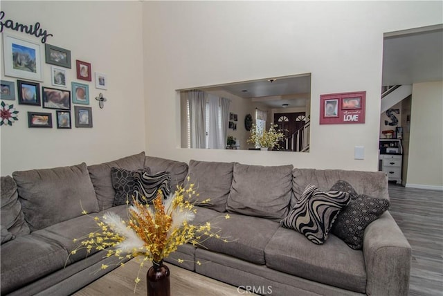 living room with a towering ceiling, baseboards, and wood finished floors