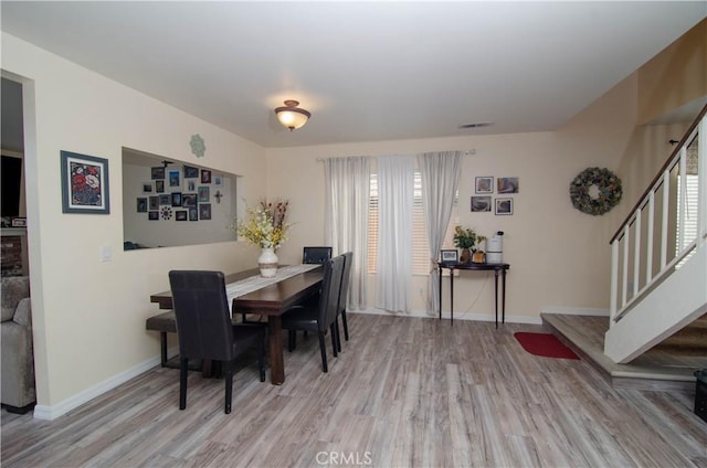 dining room with baseboards, visible vents, stairway, and wood finished floors