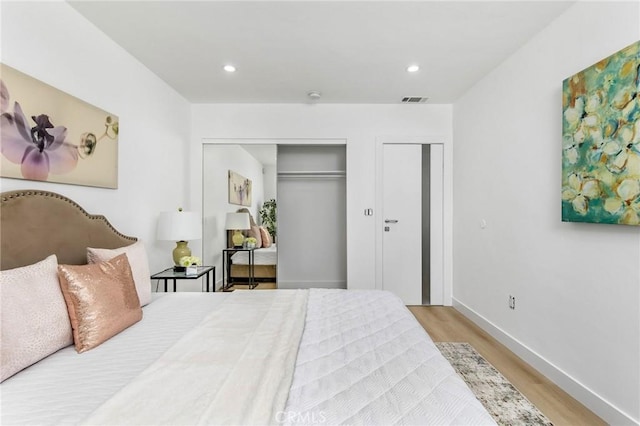 bedroom with recessed lighting, wood finished floors, visible vents, baseboards, and two closets