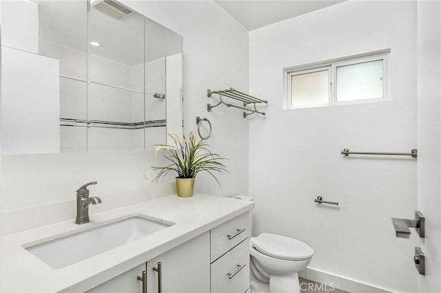 bathroom with baseboards, visible vents, vanity, and toilet