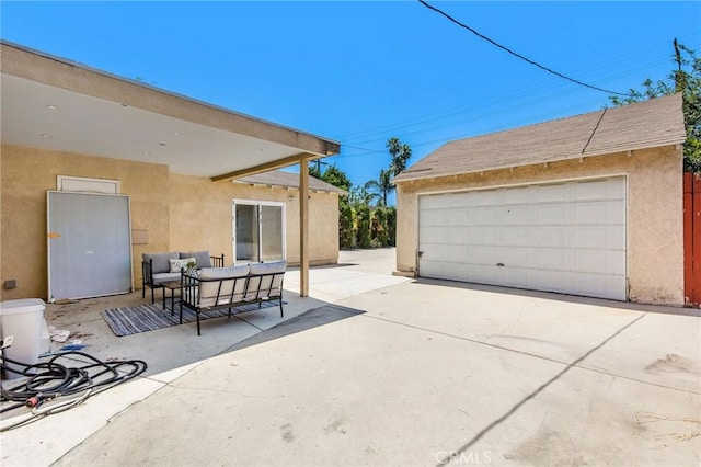 view of patio / terrace with an outdoor structure, a detached garage, and an outdoor hangout area