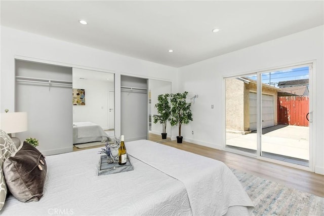 bedroom with access to outside, wood finished floors, two closets, and recessed lighting