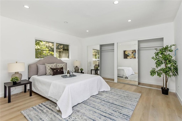 bedroom featuring baseboards, recessed lighting, light wood-type flooring, and multiple closets