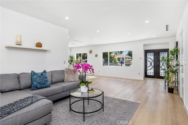 living area with visible vents, baseboards, french doors, light wood-style floors, and recessed lighting