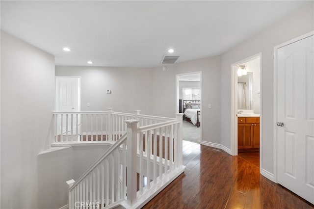 hallway with recessed lighting, visible vents, baseboards, an upstairs landing, and dark wood finished floors