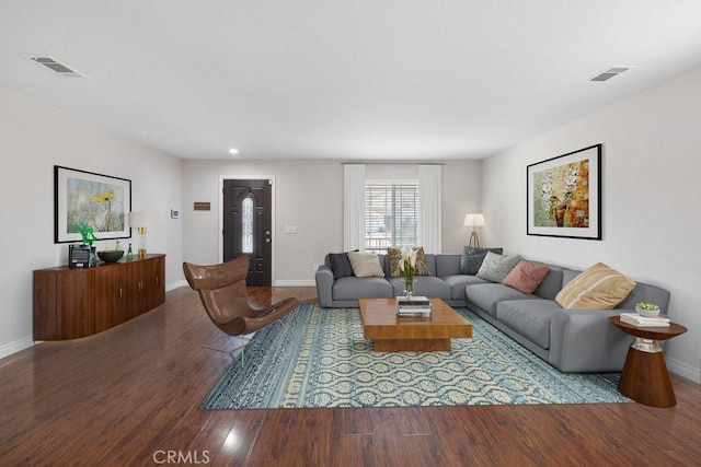 living room featuring wood finished floors, visible vents, and baseboards