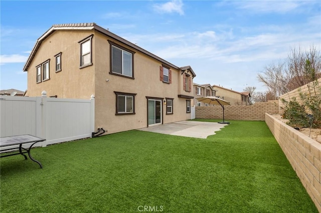 rear view of property featuring a patio area, a yard, a fenced backyard, and stucco siding