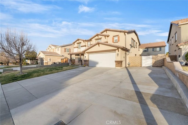 view of front facade with stucco siding, fence, a residential view, stone siding, and driveway