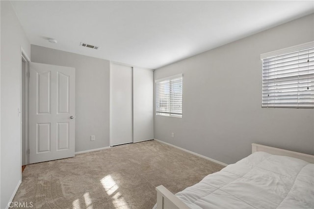 bedroom featuring a closet, carpet, visible vents, and baseboards