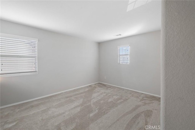 carpeted empty room with visible vents and baseboards