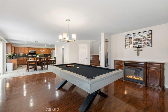 recreation room with recessed lighting, pool table, light wood-style floors, a glass covered fireplace, and a chandelier