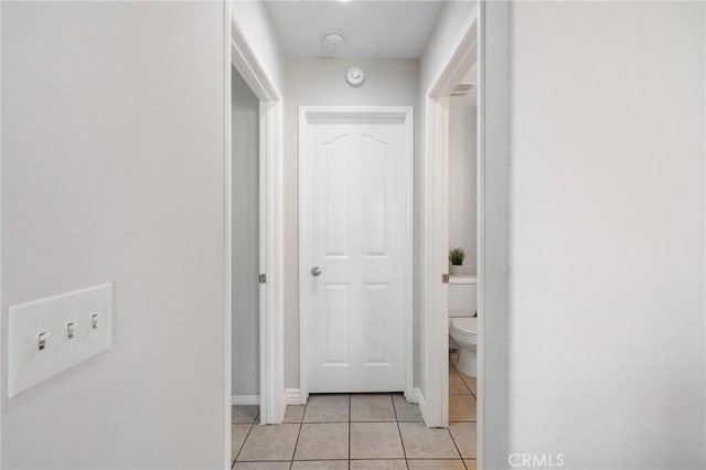 hallway with light tile patterned floors and baseboards