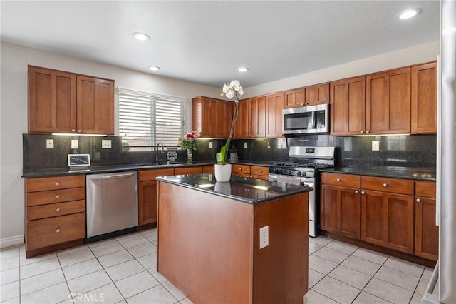 kitchen with a center island, brown cabinets, light tile patterned floors, appliances with stainless steel finishes, and a sink