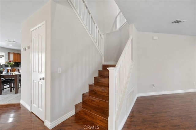 stairway with visible vents, baseboards, and wood finished floors