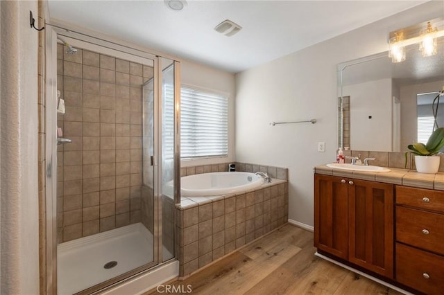 bathroom with vanity, a stall shower, wood finished floors, and a bath