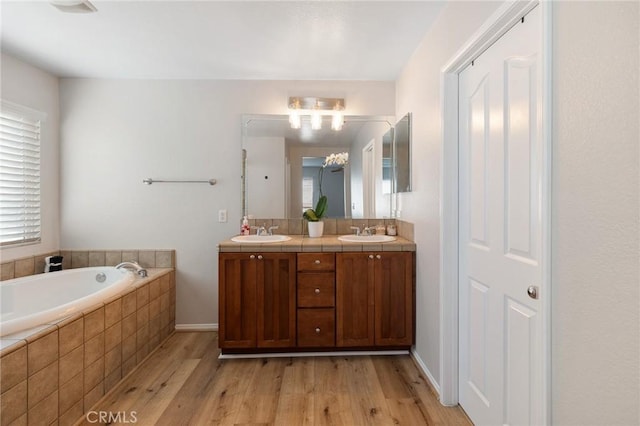 bathroom with a bath, a sink, and wood finished floors