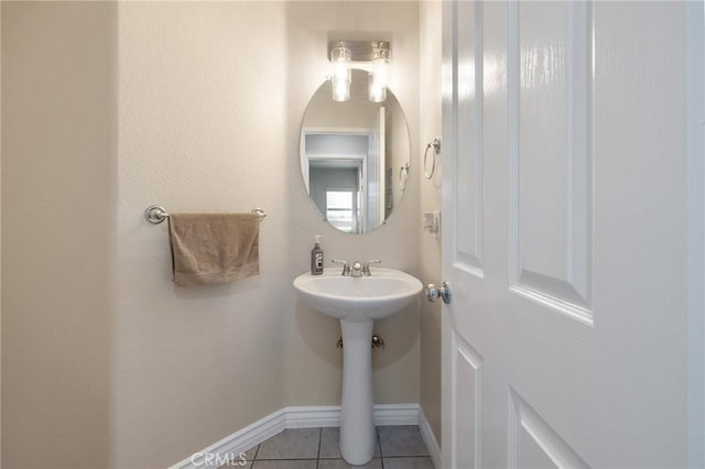 bathroom featuring tile patterned flooring, baseboards, and a sink