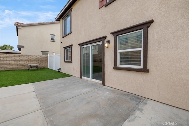 rear view of property with a yard, a patio, fence, and stucco siding