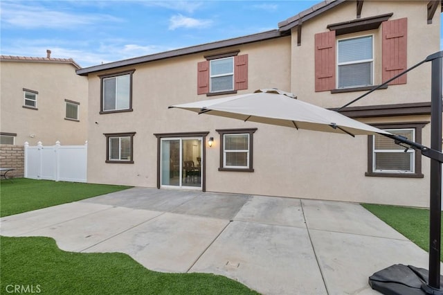 back of house featuring a patio area, fence, a lawn, and stucco siding