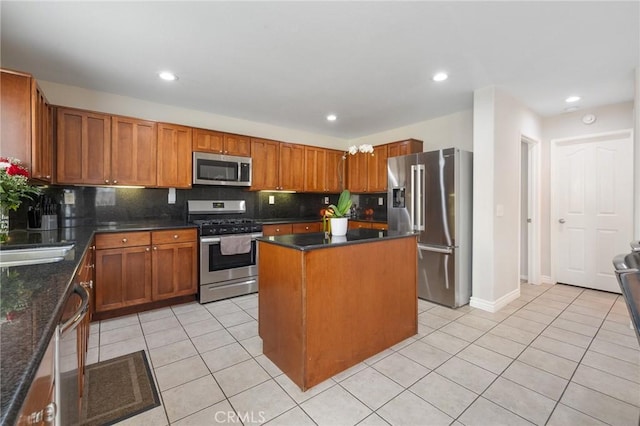 kitchen with light tile patterned flooring, a sink, a kitchen island, appliances with stainless steel finishes, and tasteful backsplash