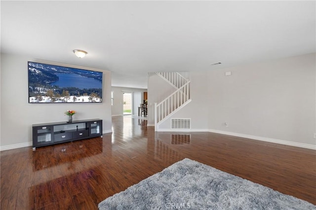 living area featuring wood finished floors, visible vents, baseboards, and stairs