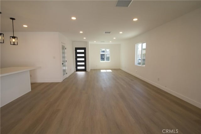 unfurnished living room featuring baseboards, visible vents, wood finished floors, and recessed lighting