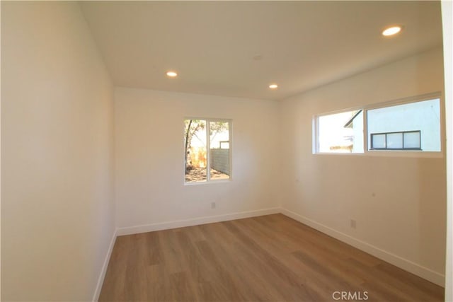 unfurnished room featuring baseboards, recessed lighting, wood finished floors, and a healthy amount of sunlight