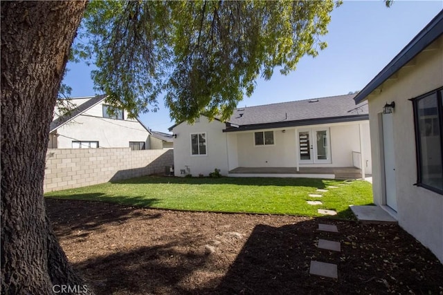 back of property featuring a yard, french doors, fence, and stucco siding