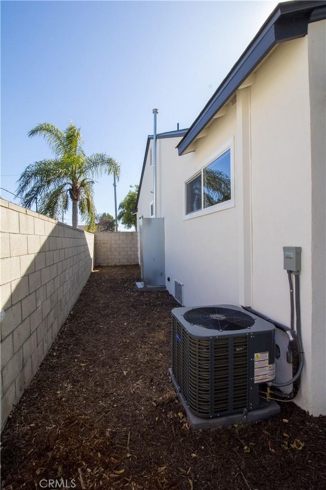 exterior space with central AC unit, a fenced backyard, and stucco siding