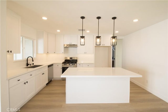 kitchen featuring white cabinets, a center island, stainless steel appliances, light wood-style floors, and a sink