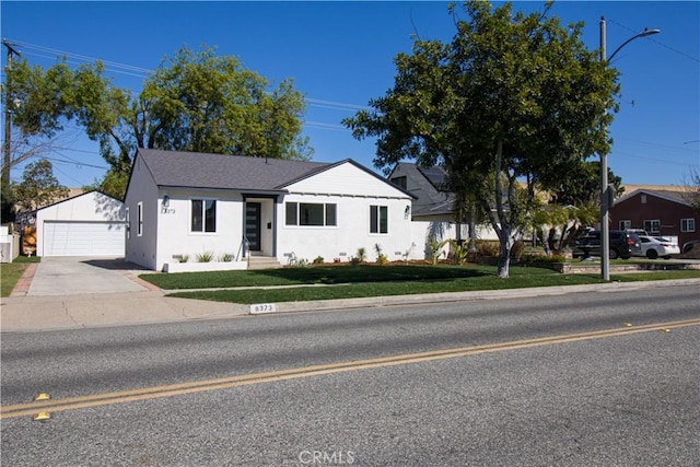 view of front of house featuring stucco siding, a shingled roof, a garage, an outdoor structure, and a front lawn