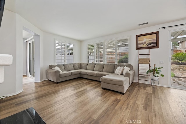 living area featuring wood finished floors, visible vents, and a healthy amount of sunlight