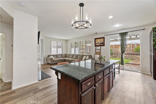 kitchen with baseboards, dark brown cabinetry, decorative light fixtures, light wood-type flooring, and a notable chandelier