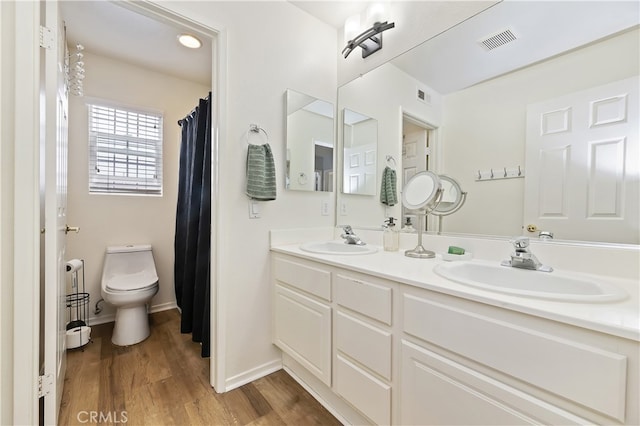 bathroom featuring a sink, visible vents, toilet, and wood finished floors