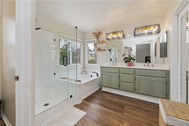 bathroom with wood finished floors, double vanity, a stall shower, a sink, and a bath