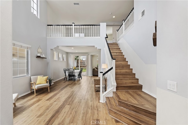 foyer featuring visible vents, stairs, a high ceiling, and wood finished floors