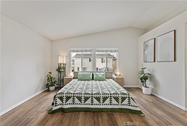 bedroom with lofted ceiling, wood finished floors, and baseboards