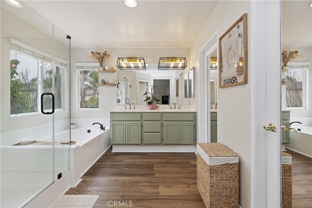 bathroom with a bath, wood finished floors, and a sink