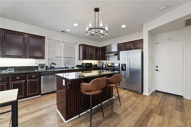 kitchen with light wood finished floors, stainless steel appliances, an inviting chandelier, and a sink