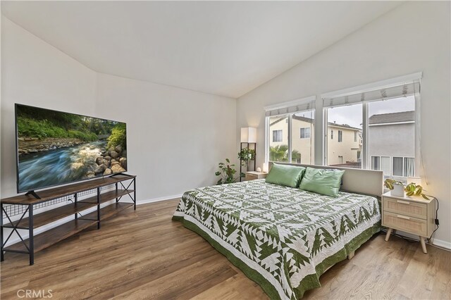 bedroom with baseboards, wood finished floors, and vaulted ceiling