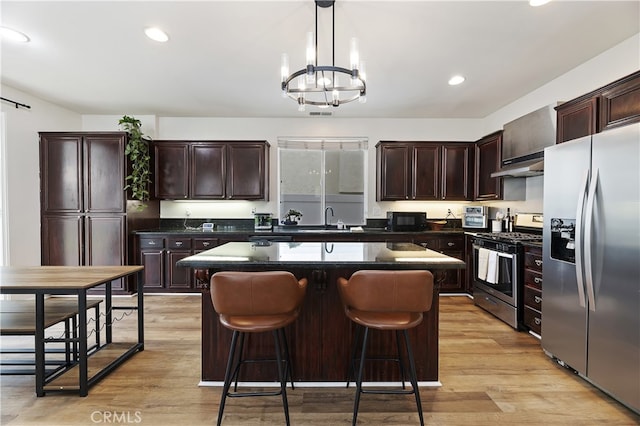 kitchen featuring light wood finished floors, stainless steel appliances, an inviting chandelier, and a sink