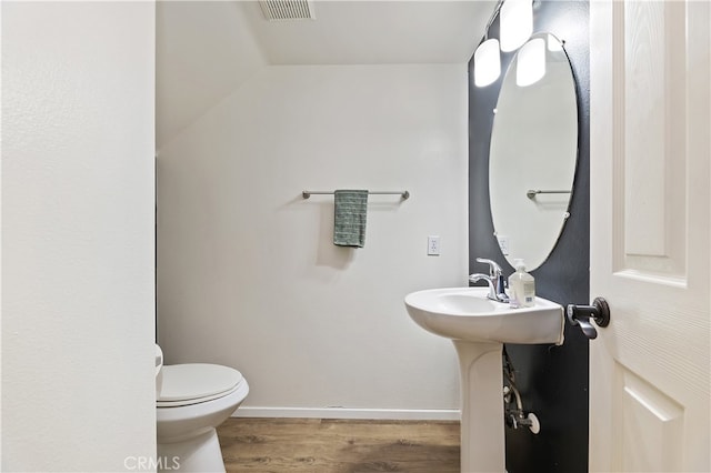 half bathroom with visible vents, baseboards, toilet, and wood finished floors