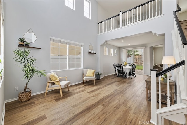 sitting room with stairway, baseboards, a high ceiling, and wood finished floors